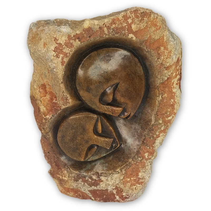 A serpentine stone carving of a couple in an embrace, hand-carved in Zimbabwe.