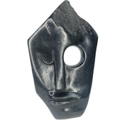 A black, abstract-style face sculpture made of stone, hand-crafted in Zimbabwe.