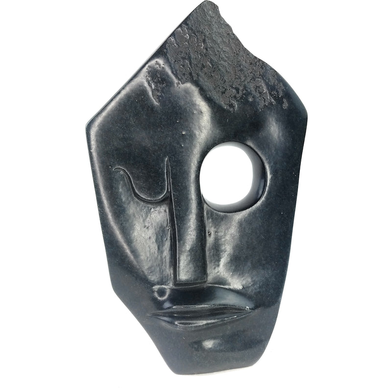 A black, abstract-style face sculpture made of stone, hand-crafted in Zimbabwe.