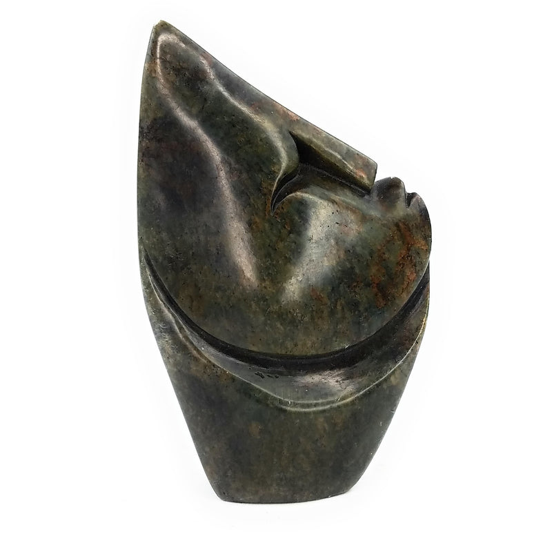 A hand-carved stone sculpture of an abstract face, with a textured dark stone finish.