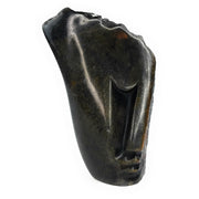 A hand-carved stone sculpture of an abstract face, with a dark, mottled appearance, indicative of the traditional Shona stone carving art.