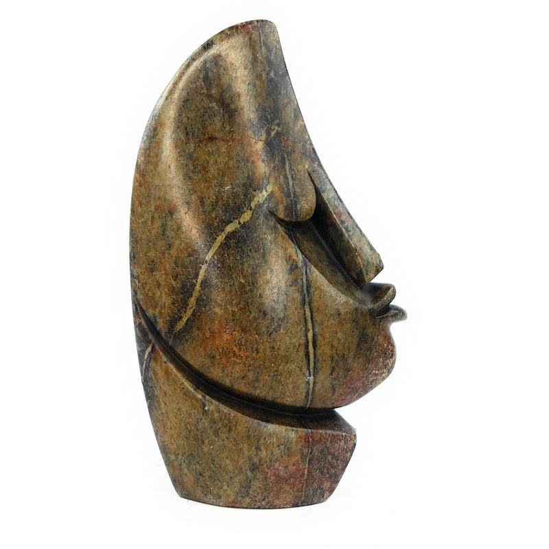 A hand-carved stone sculpture of an abstract face, with a rough, textured surface in brown and black tones.