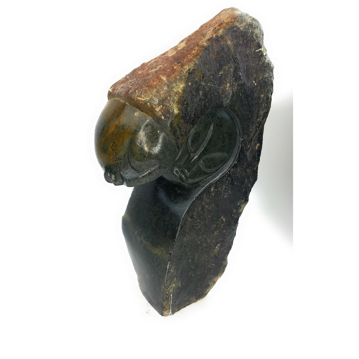 A hand-carved stone sculpture of a man and a woman in an eternal embrace, primarily in dark tones.