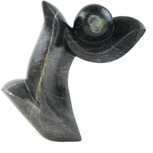 A black, abstract-style Shona sculpture made of stone, depicting an artistic representation that may vary slightly in color, size, and motif due to its handmade nature.