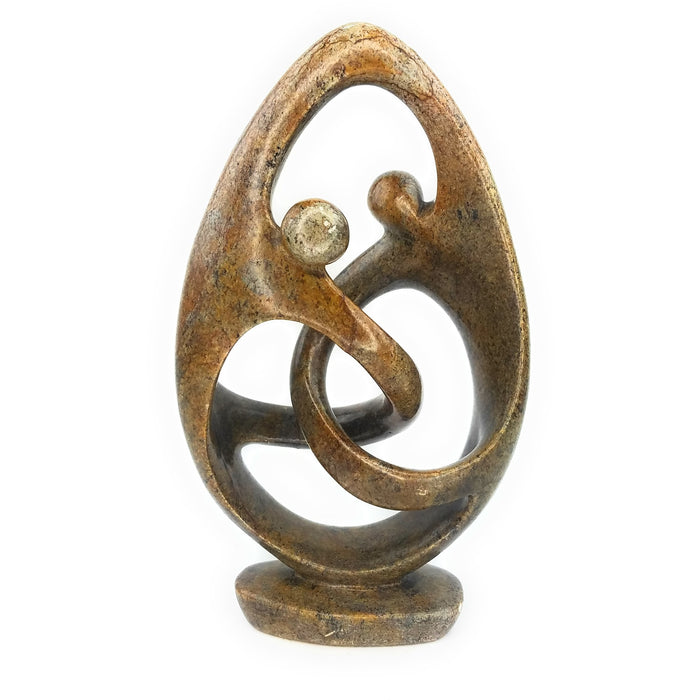 A hand-carved stone sculpture of a dancing couple, brown in color, placed on a flat surface.