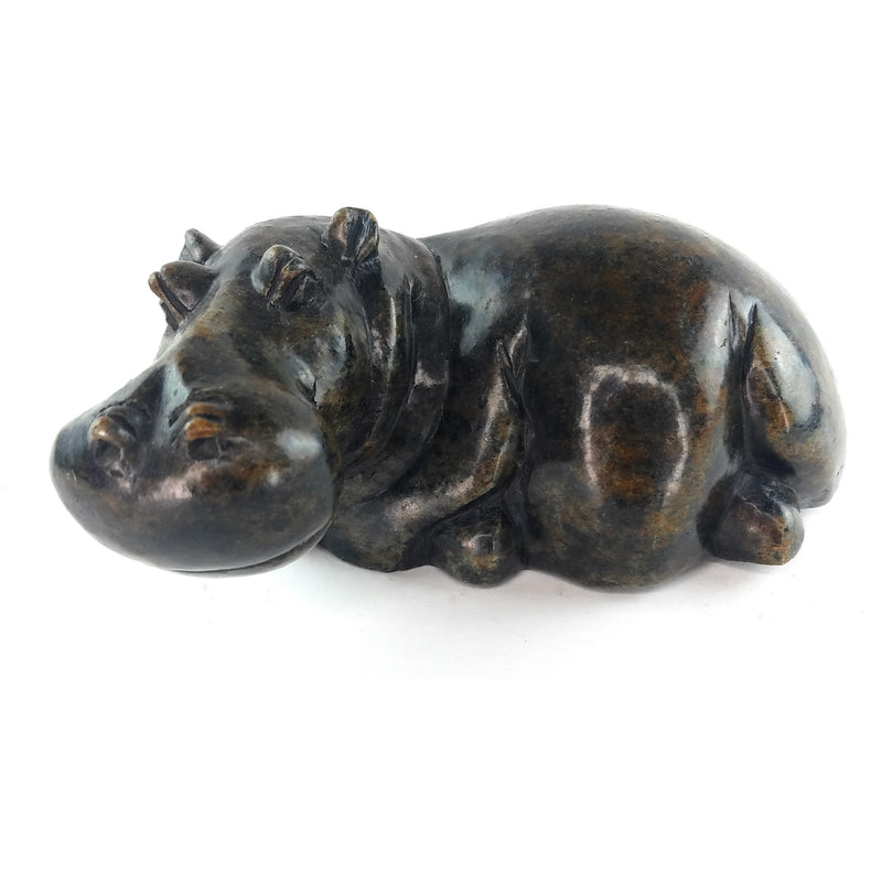 A hand-carved serpentine stone sculpture of a hippo, resting in a curved position.
