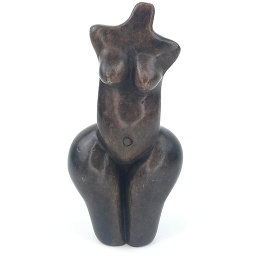 A handcrafted stone sculpture of a female torso, with exaggerated hips and breasts, on a white background.