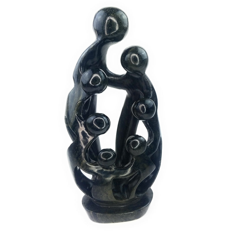 A hand-carved serpentine stone sculpture depicting a family of seven figures in a protective embrace, with intricate detailing and a dark-colored finish.