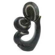 A hand-carved stone sculpture of a kissing couple, primarily in dark tones, against a white background.