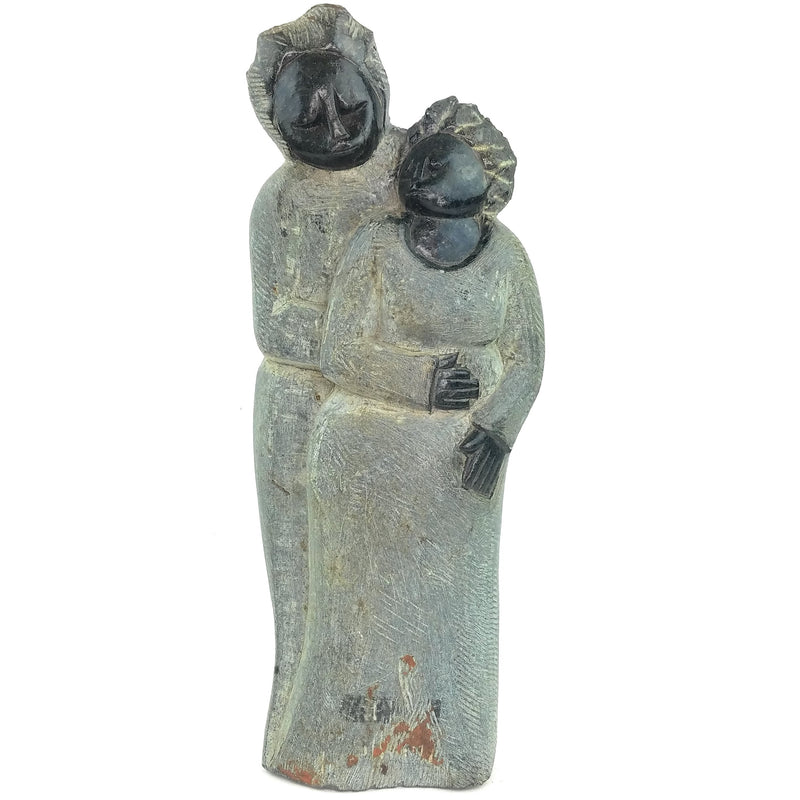 A hand-carved stone sculpture of a mother and daughter, with a more robust and taller daughter beside a shorter, rounder mother, both with intricate facial details.