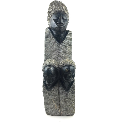 A hand-carved stone sculpture of a mother and children, with a serpentine texture, primarily in darker tones.