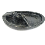 A serpentine stone soap dish with a floating pelican bird design, handcrafted in Zimbabwe.