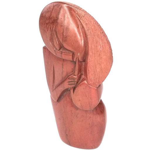 A red jasper stone pipe smoker hand carved in Zimbabwe, showing an abstract representation of a figure with a pipe.