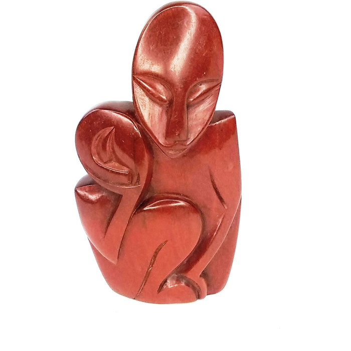 A hand-carved red jasper stone sculpture of a mother embracing her child.