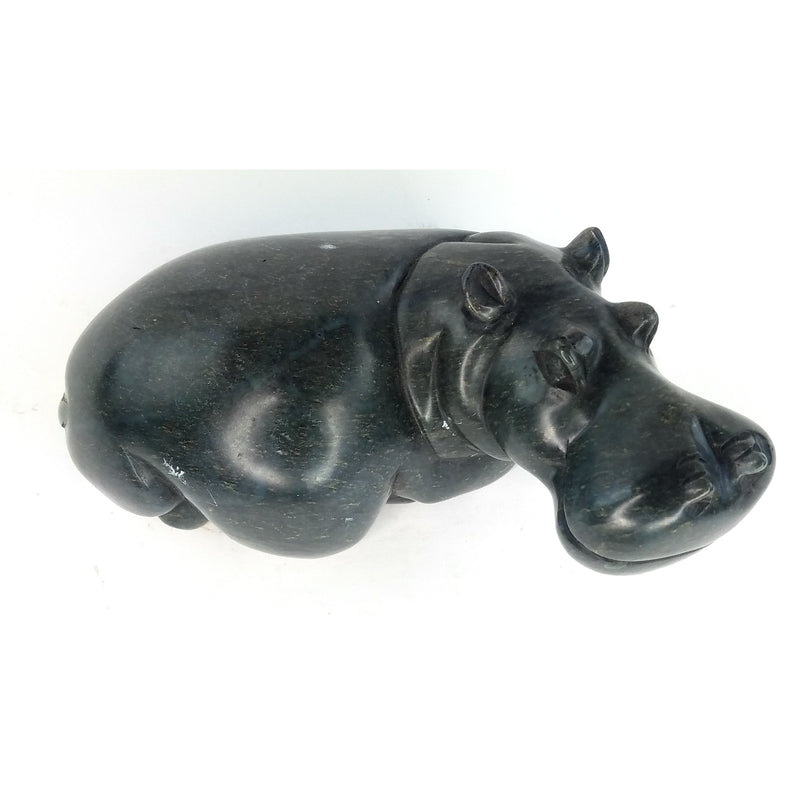 A hand-carved stone sculpture of a hippo, primarily in a dark color, with a textured surface and no visible base.