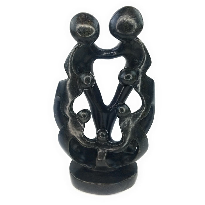 A hand-carved stone sculpture depicting a family of seven, with a mother, father, and five children, in black.