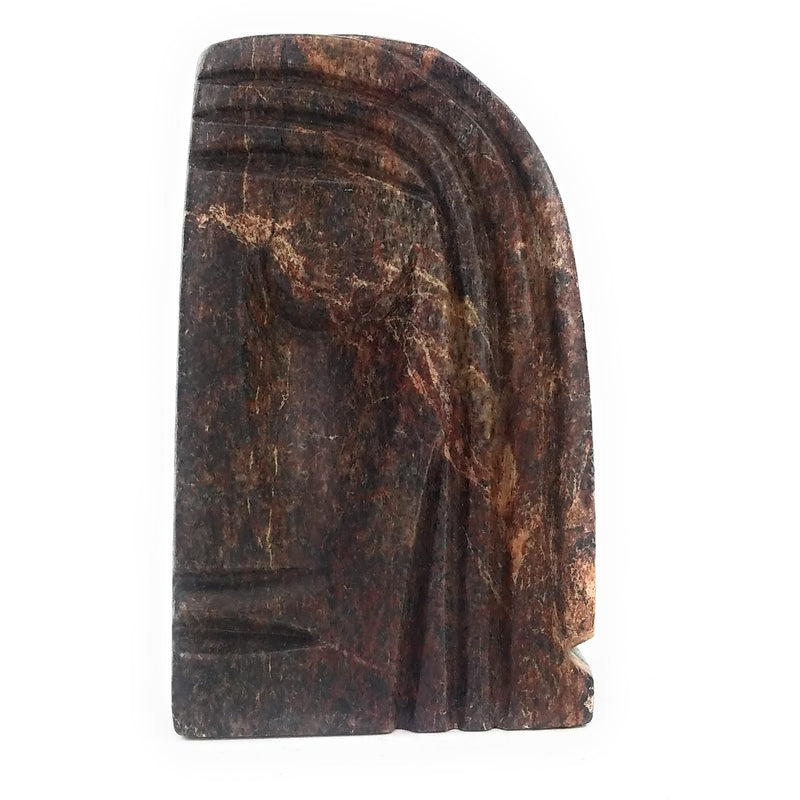 A sculpture of an abstract face with intricate patterns, predominantly in shades of brown and black, representing the Watchful Spirit.