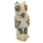 A hand-carved stone owl sculpture, primarily in shades of grey and beige, with a textured surface indicating its handcrafted nature.