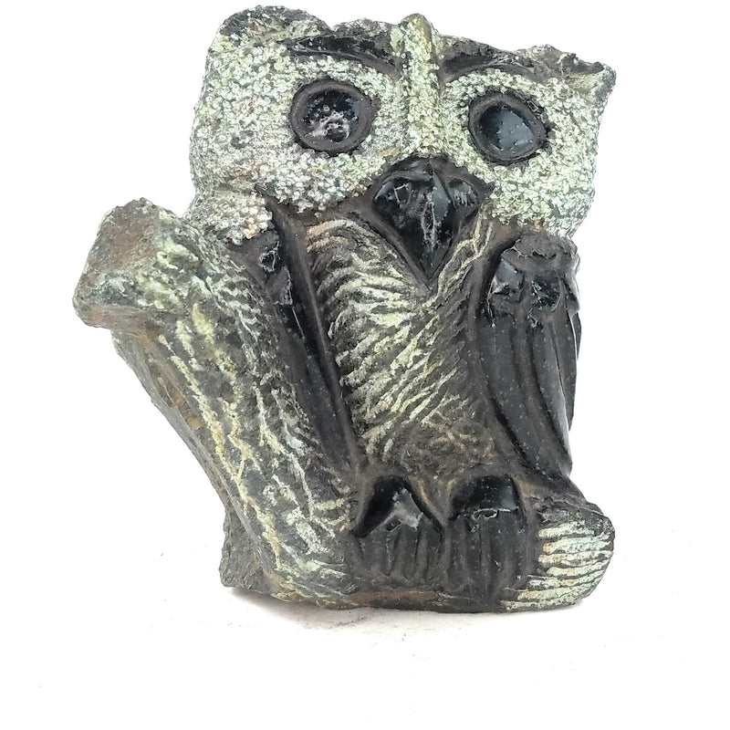 A hand-carved stone sculpture of an owl with intricate detailing and a textured surface, primarily in dark tones.